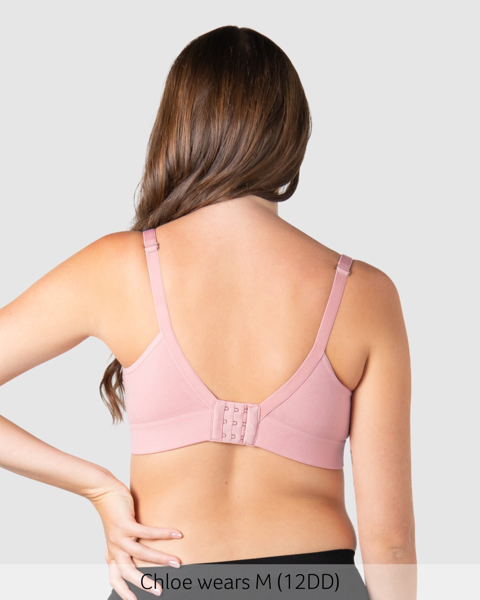 Woman wearing a pink bra against a plain background