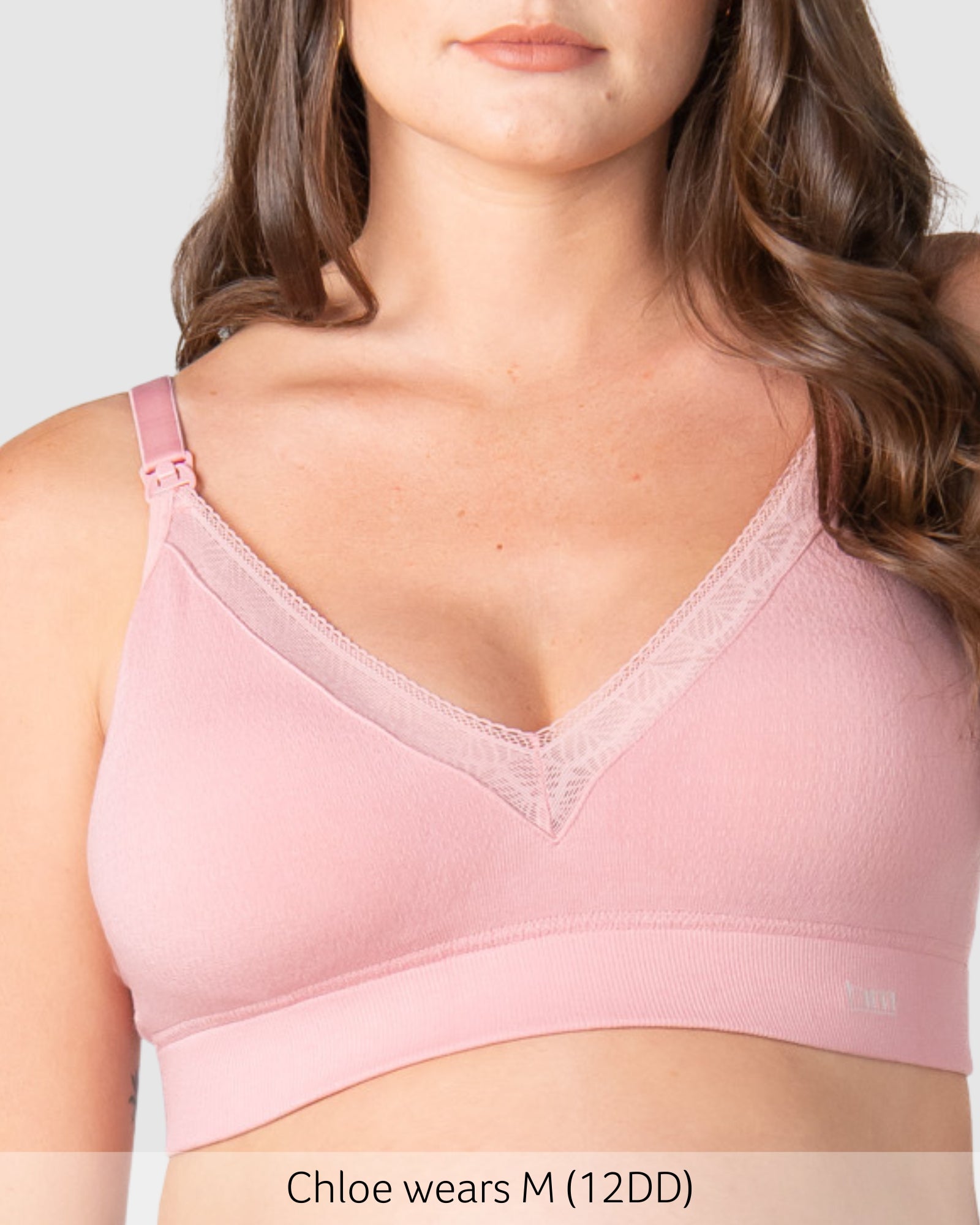Woman wearing a pink bra with visible branding, on a plain background.