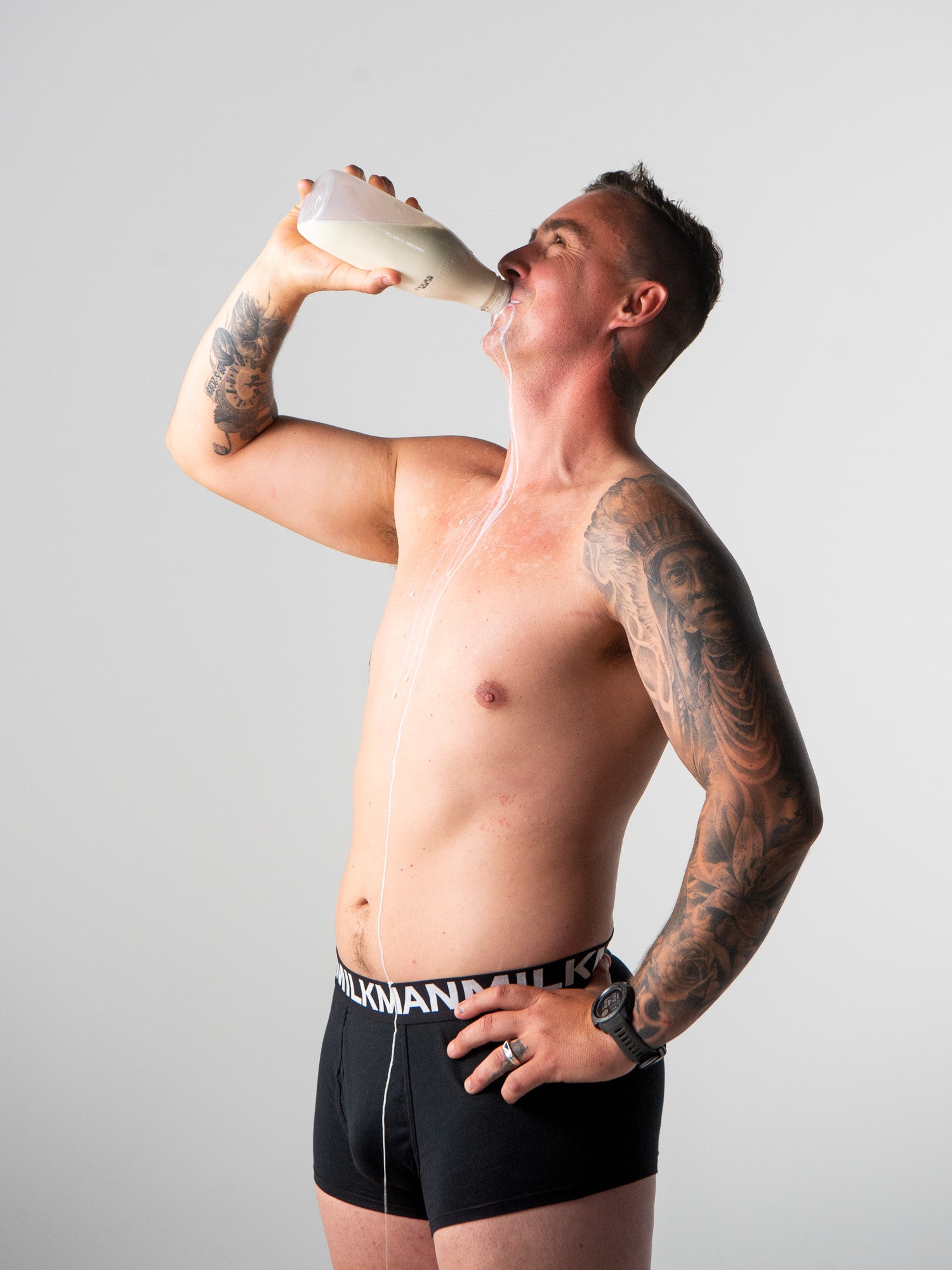 Man drinking from a bottle against a plain background
