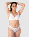 Taitiana, a mother of 2, confidently showcases the best-selling nursing lingerie set from Hotmilk Lingerie. She pairs the True Luxe nursing bra in white with the matching semi-sheer floral lace bikini. This set allows you to embrace your individual style while receiving expert support and lift for larger bust sizes up to J cup. It's the perfect choice for capturing the radiant beauty of maternity photo shoots